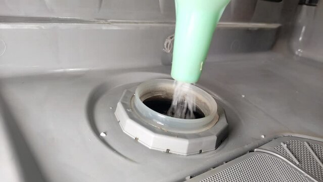 Housekeeper pouring dishwasher salt into the water softener hole