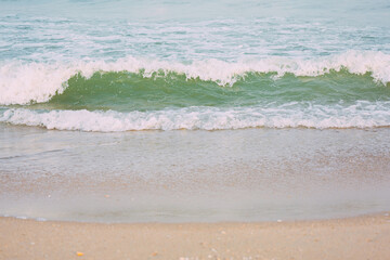 The sea waves at the sandy beach are rolling towards the shore.