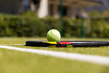 Close-up of tennis racket and ball by white marking on grassy field at tennis court