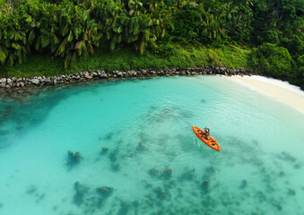 Drone's Eye View: Unrecognizable Woman Canoeing in a Tropical Exotic Destination. Aerial Perspective of an Unrecognizable Tourist Exploring Exotic Waters