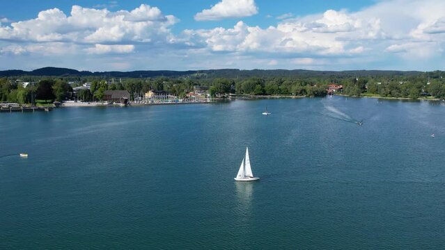 Aerial drone view of yacht on Starnberg See lake, Bavaria Germany. Recreation and relaxation area with beach, cafe and forest.