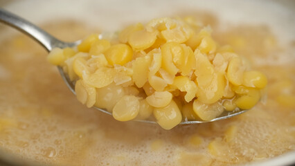 Cooking yellow split peas in boil water. Chef stir boiling yellow split peas with spoon