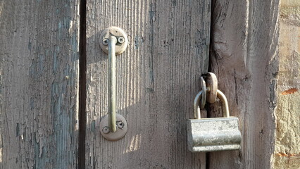 old wooden door with metal handle and padlock. close up elements 