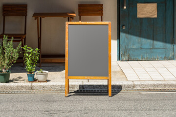 Blank white outdoor advertising stand/sandwich board mock up template. Clear street signage board placed by an outdoor dinning area of a restaurant. Background texture of standee on street.
