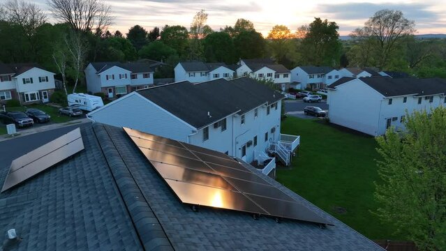 Solar panels on residential home during spring sunset. Aerial establishing shot of clean energy from photovoltaic cell array.