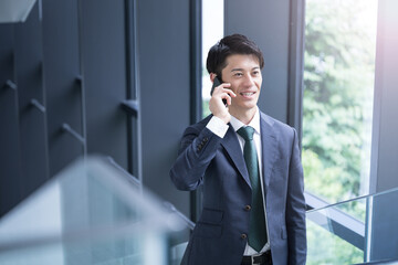 Handsome Asian (Japanese) businessman in suit making a phone call Business scene