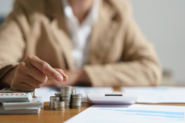 Businesswoman putting a coin on the pile of coins with saving money idea for investment business