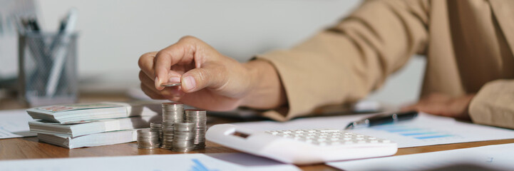 Businesswoman putting a coin on the pile of coins with saving money idea for investment business