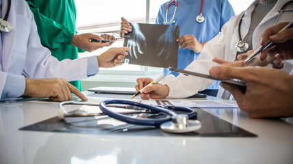 Medical team meeting with doctors in white lab coats and surgical gowns sitting at table discussing patient history. success of medical health care doctor work concept