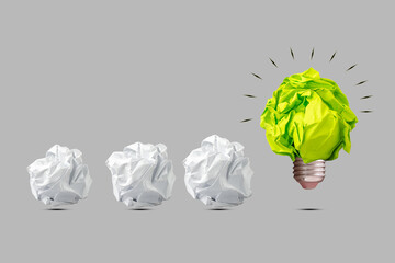 Crumpled green paper light bulb, and white paper balls. Isolated on a grey background. The concept of inspiration, new ideas. Business.