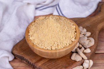 Ginger powder on wooden background. Powdered dried ginger in wooden bowl