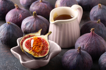 Ripe purple fig fruits with honey on dark background.