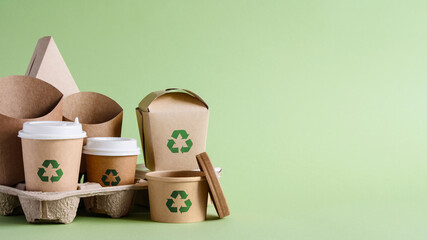 Recycling concept. A set of disposable paper tableware with a recycling sign on a green background....