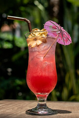 tropical singapore sling cocktail in tall glass at garden bar - 606708111
