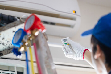 Technician man operating air conditioner with remote control, Repair and maintenance concepts