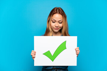 Naklejka premium Teenager girl over isolated blue background holding a placard with text Green check mark icon