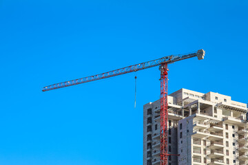 Construction crane and unfinished building against blue sky