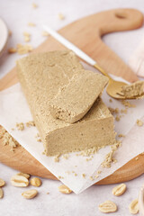 Board with tasty halva and peanuts on white background