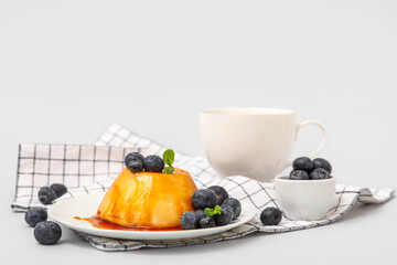 Plate of delicious pudding with caramel syrup, blueberries and mint on grey background