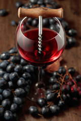 Red wine, corkscrew, and blue grapes.