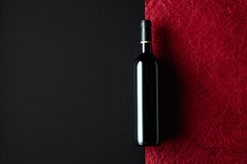 Bottle of red wine on a background of the old red crumpled paper.