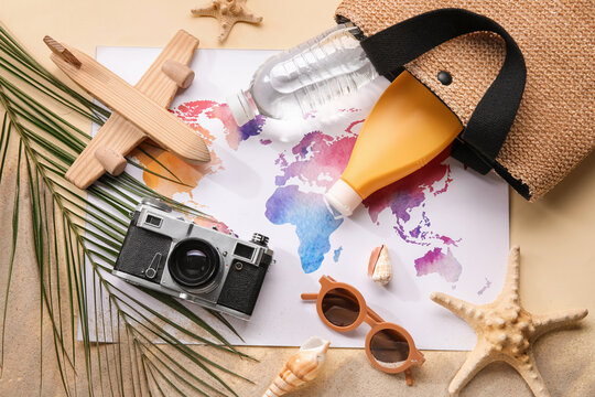 Composition with world map, bottle of sunscreen cream, photo camera and sunglasses on beige background