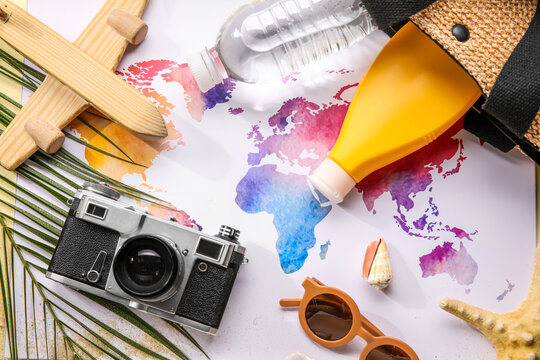 Composition with world map, bottle of sunscreen cream, photo camera and sunglasses on beige background