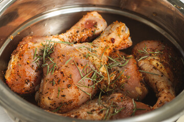 Raw chicken legs with spices. Marinated chicken with rosemary and paprika. Uncooked meat. Raw meat in bowl. Homemade barbecue. Meat and herbs.