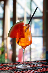 Summer alcoholic drink aperol spritz with a slice of watermelon on the bar counter.