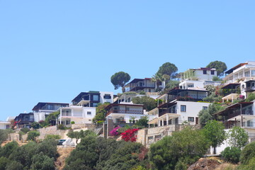 Fototapeta na wymiar View of houses and mountains overgrown with desom on the coast of the Aegean Sea in Turkey. Türkiye, May 2023.