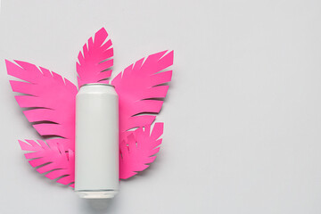 Composition with can of fresh soda and paper leaves on grey background