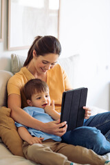 Woman at home educating her young son showing a tablet