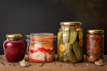 Preserving vegetables for the winter, canned vegetables in jars on a wooden table against a brown wall, pickled or fermented vegetables, copy space