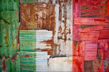 Flag of Italy on rusty corrugated iron sheets forming a wall or a fence