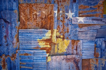 Flag of Kosovo on rusty corrugated iron sheets forming a wall or a fence