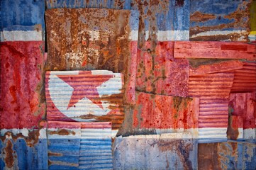 Shot of the flag of North Korea painted on rusty overlapping corrugated iron sheets