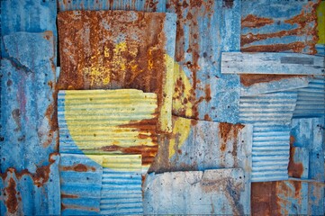 Shot of the flag of Palau painted on rusty overlapping corrugated iron sheets