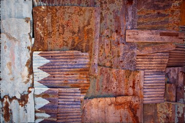 Abstract background of the flag of Qatar painted onto a wall of rusty corrugated iron sheets