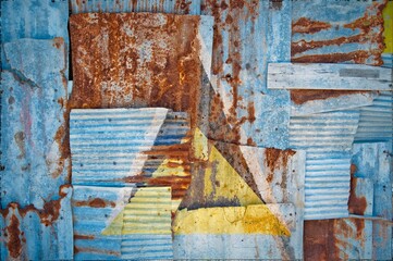 Flag of Saint Lucia painted onto rusty corrugated iron sheets overlapping to form a wall or fence
