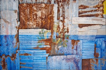 Flag of San Marino painted onto rusty corrugated iron sheets overlapping to form a wall or fence