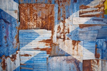 Flag of Scotland painted onto rusty corrugated iron sheets overlapping to form a wall or fence