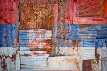 Flag of Serbia painted onto rusty corrugated iron sheets overlapping to form a wall or fence