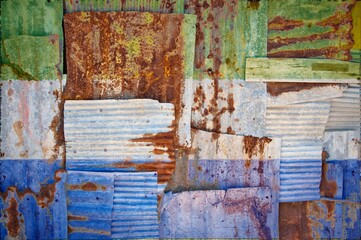 Flag of Sierra Leone painted onto rusty corrugated iron sheets overlapping to form a wall or fence