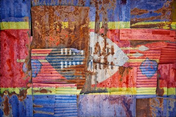 Flag of Swaziland painted onto rusty corrugated iron sheets overlapping to form a wall or fence