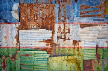 Flag of Uzbekistan painted onto rusty corrugated iron sheets overlapping to form a wall or fence