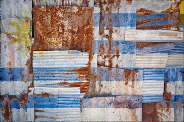 Flag of Uruguay painted onto rusty corrugated iron sheets overlapping to form a wall or fence