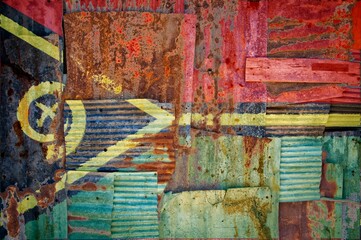 Flag of Vanuatu painted onto rusty corrugated iron sheets overlapping to form a wall or fence
