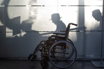 Las sombras de personas pasan sobre una silla de ruedas que espera en una estación de tren.