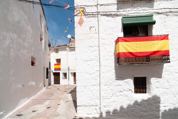 Fototapeta premium Vista de las calles blancas de un típico pueblo español con la bandera de España.