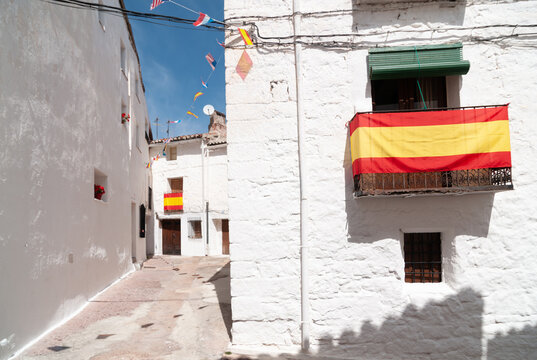 Vista de las calles blancas de un típico pueblo español con la bandera de España.